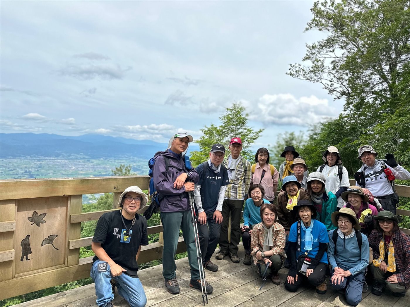 南昌山の山頂の展望デッキに並ぶ参加者たち。背後には雲の低い空と、はるかに広がる盛岡南部の平野が見えている。